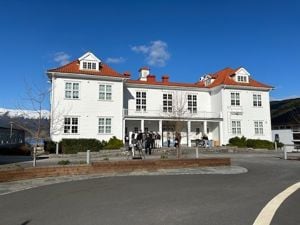 Kvitt trebygg med rødt tak med knall blå himmel i bakgrunnen.