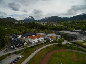 oversiktsbilde over Firda vgs og Trivselshallen med grå skyer i bakgrunnen